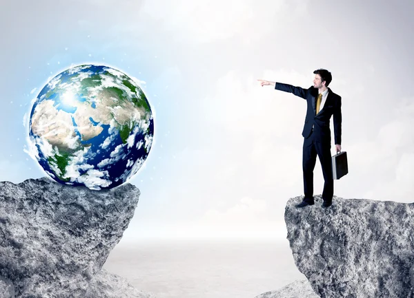 Businessman on rock mountain with a globe — Stock Photo, Image