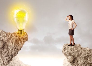 Businesswoman on rock mountain with idea bulb clipart