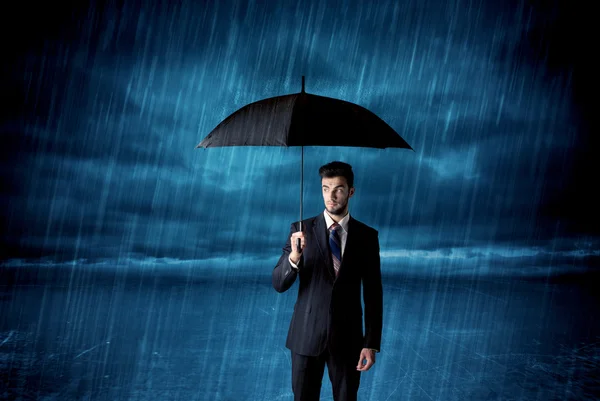 Business man standing in rain with an umbrella — Stock Photo, Image