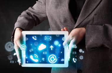 Mavi teknoloji simgeleri ve sembolleri olan bir tablet tutan kişi