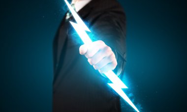 Business man holding glowing lightning bolt in his hands clipart
