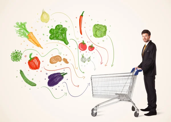 Businessman with shopping cart with vegetables — Stock Photo, Image