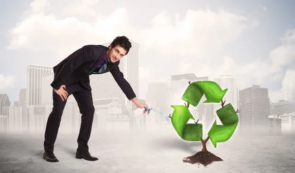 Business man watering green recycle sign tree on city background — Stock Photo, Image