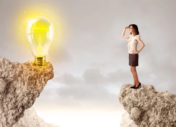 Businesswoman on rock mountain with idea bulb — Stock Photo, Image