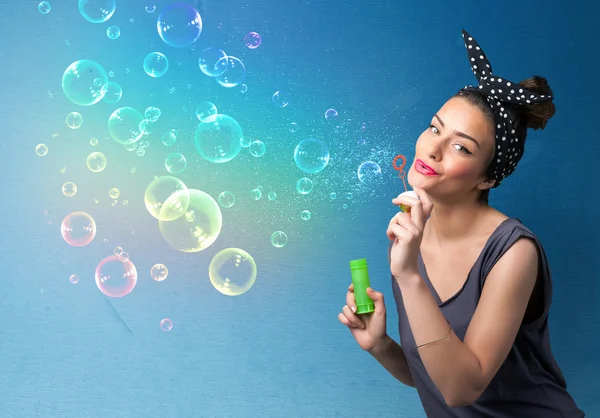 Pretty lady blowing colorful bubbles on blue background — Stock Photo, Image