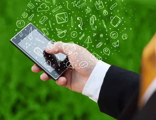 Hand holding smartphone with hand drawn media icons and symbols — Stock Photo, Image