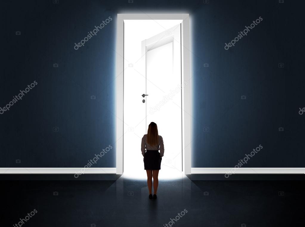 Business woman looking at big bright opened door