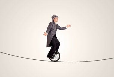 Extreme business man riding unicycle on a rope clipart