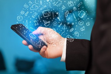 Elle çizilmiş medya simgeleri ve sembolleri ile akıllı telefonu tutmak