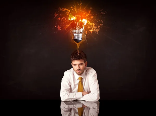 Businessman sitting under a blowing idea bulb — Stock Photo, Image