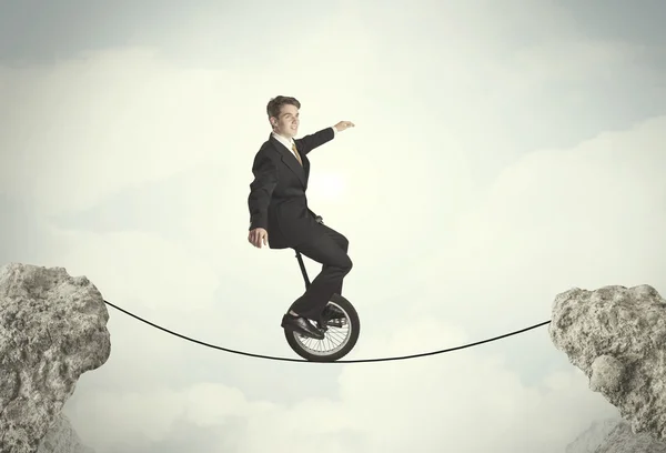 Brave business man riding an mono cycle between cliffs — Stock Photo, Image