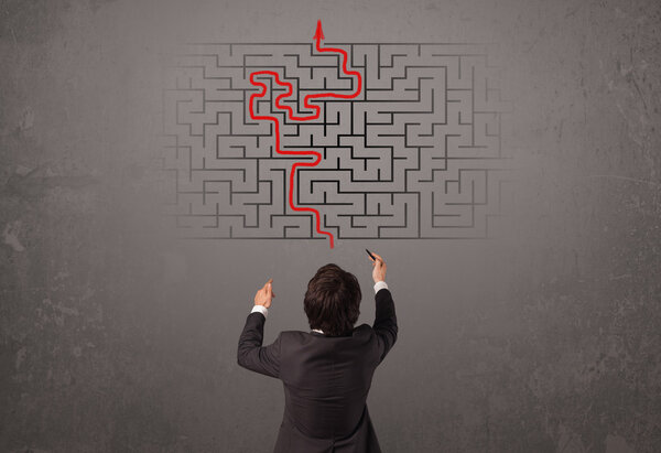 Business man looking at a maze and the way out 