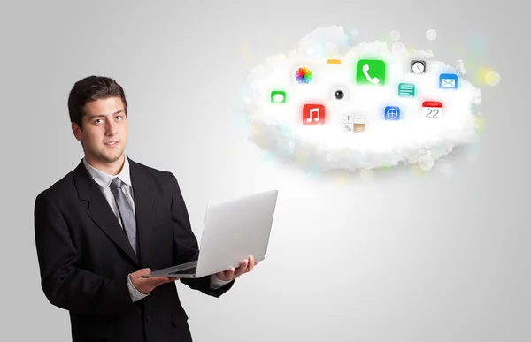 Young man presenting cloud with colorful app icons and symbols — Stock Photo, Image