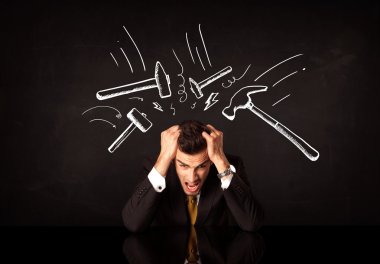 Depresyondaki işadamı çekiç izlerinin altında oturuyor
