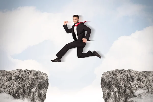 Hombre de negocios divertido saltando sobre rocas con brecha — Foto de Stock