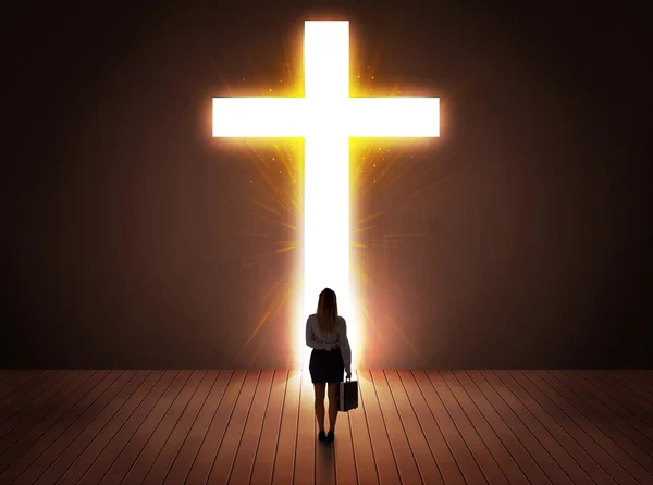 Женщина смотрит на яркий знак креста — стоковое фото