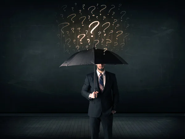 Empresário com guarda-chuva e um monte de pontos de interrogação desenhados — Fotografia de Stock