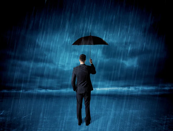 Business man standing in rain with an umbrella — Stock Photo, Image