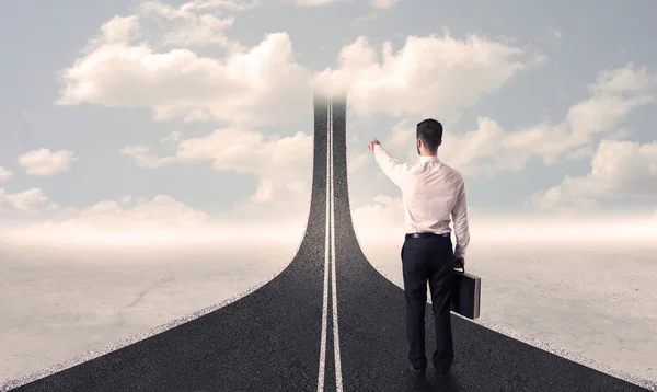 Businessman looking at 3d road that goes up in the sky — Stock Photo, Image