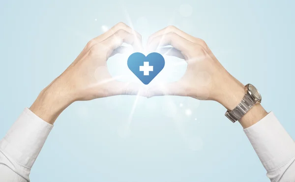 Handen creëren van een vorm met hart blauw kruis — Stockfoto