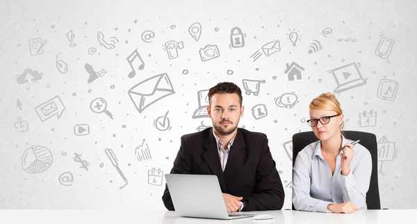 Geschäftsmann und Frau sitzen mit handgezeichneten Medien am Tisch — Stockfoto