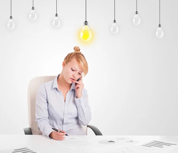Business woman sitting at table with idea light bulbs Stock Image