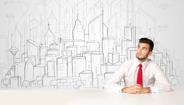 Biznesmen siedzi przy białym stole z ręcznie rysowanymi budynkami — Zdjęcie stockowe