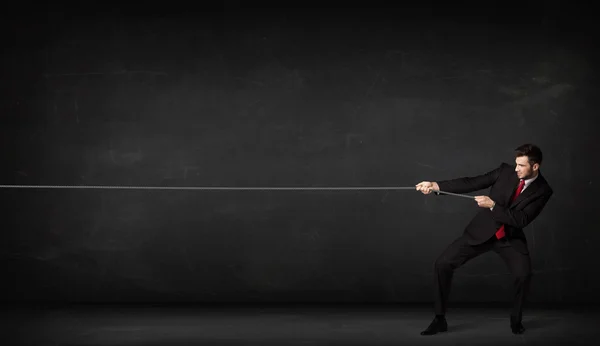 Бізнесмен тягне мотузку на сірому фоні — стокове фото