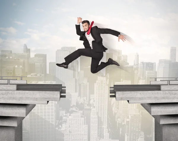Энергичный бизнесмен, прыгающий через мост с разломом — стоковое фото