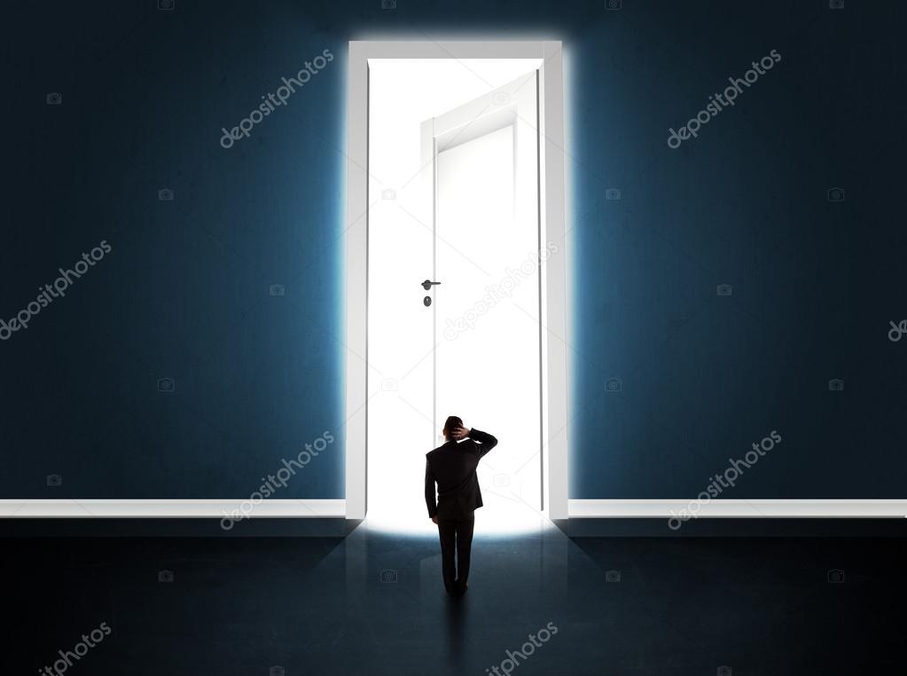 Business man looking at big bright opened door