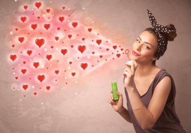 Güzel genç kız kırmızı kalp sembolleri üflüyor. 