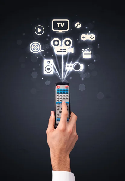 Hand with remote control and media icons — Stock Photo, Image