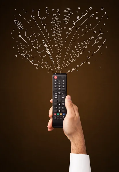 Hand with remote control and curly lines — Stock Photo, Image