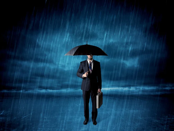 Business man standing in rain with an umbrella — Stock Photo, Image