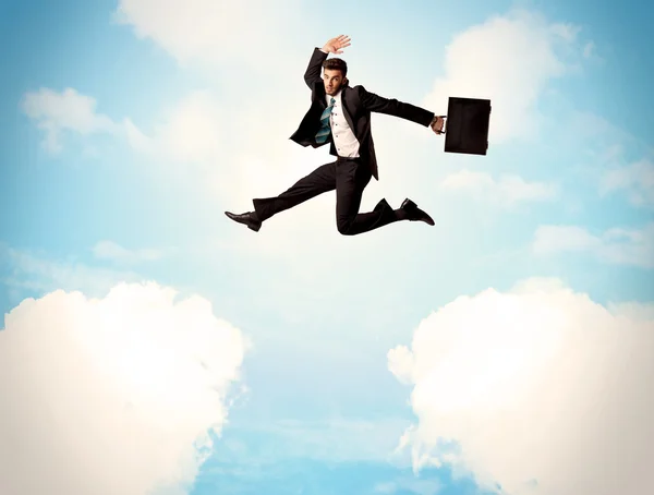 Business person jumping over clouds in the sky