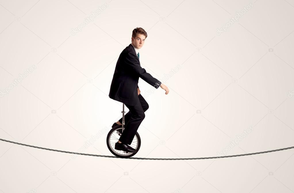 Extreme business man riding unicycle on a rope