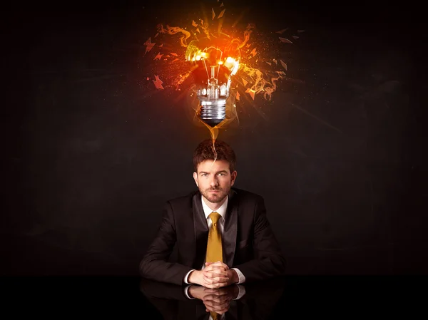 Businessman sitting under a blowing idea bulb — Stock Photo, Image