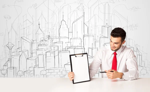 Empresário sentado à mesa branca com edifícios desenhados à mão — Fotografia de Stock