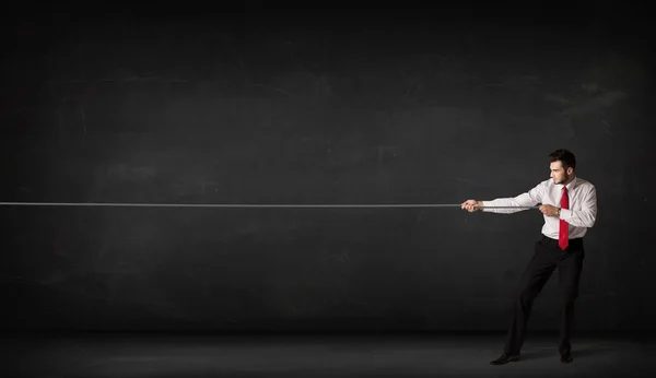 Businessman pulling rope on grey background — Stock Photo, Image