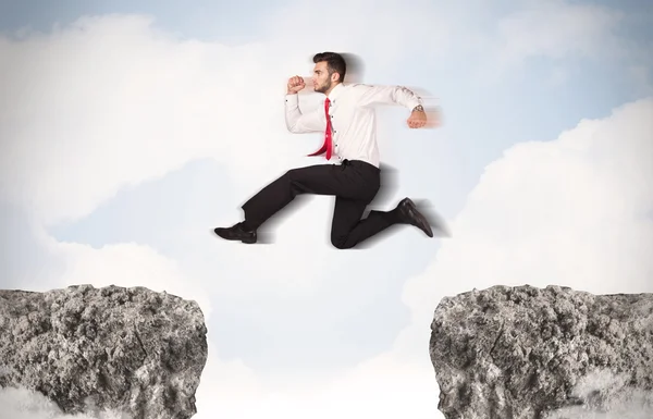 Hombre de negocios divertido saltando sobre rocas con brecha — Foto de Stock