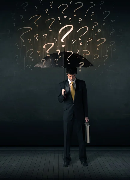 Businessman with umbrella and a lot of drawn question marks — Stock Photo, Image