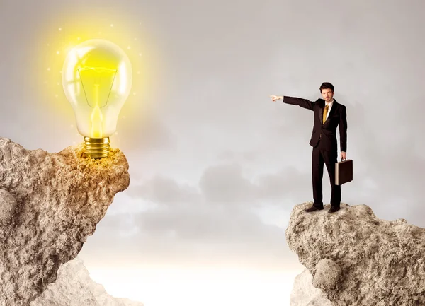 Businessman on rock mountain with idea bulb — Stock Photo, Image