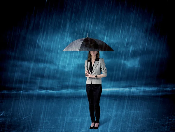Mujer de negocios de pie bajo la lluvia con un paraguas —  Fotos de Stock