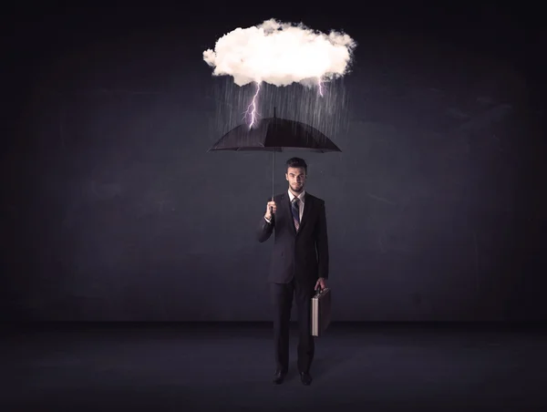 Empresario de pie con paraguas y pequeña nube de tormenta —  Fotos de Stock