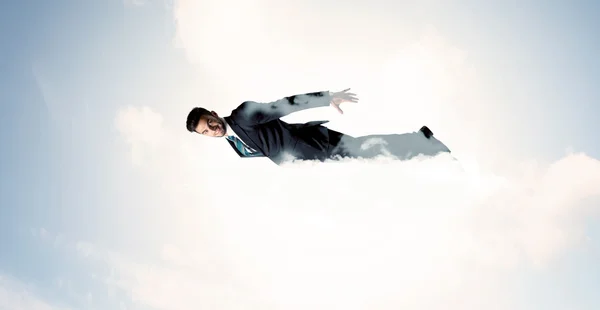 Affärsman flyger som en superhjälte i molnen på himlen — Stockfoto