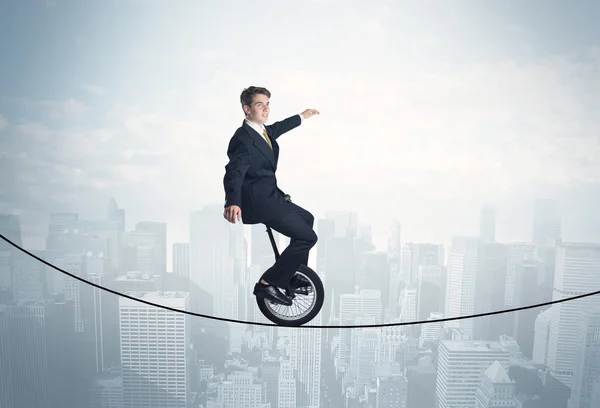 Een dappere man op een monocycle op een touw boven het stadsgezicht. — Stockfoto