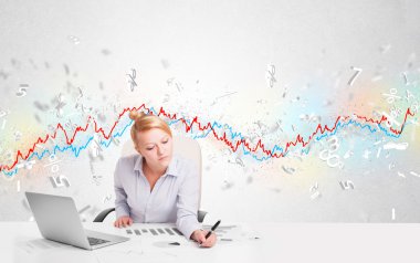 Borsa grafiğiyle masada oturan iş kadını. 
