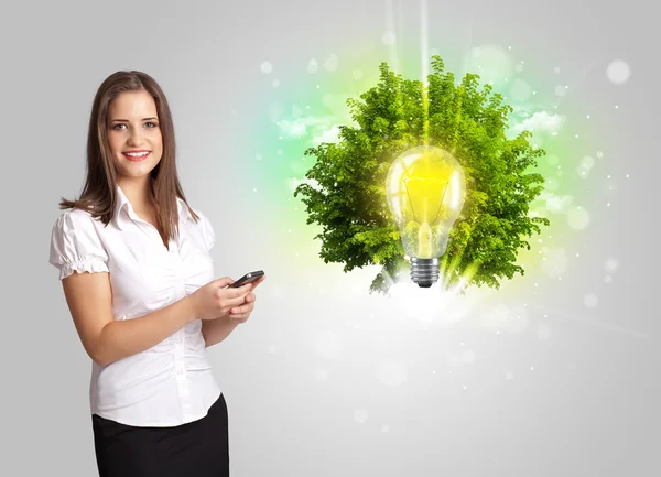 Giovane ragazza che presenta idea lampadina con albero verde — Foto Stock