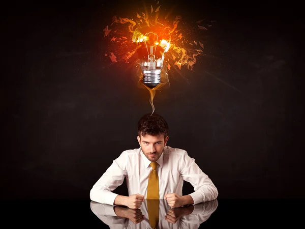 Businessman sitting under a blowing idea bulb — Stock Photo, Image