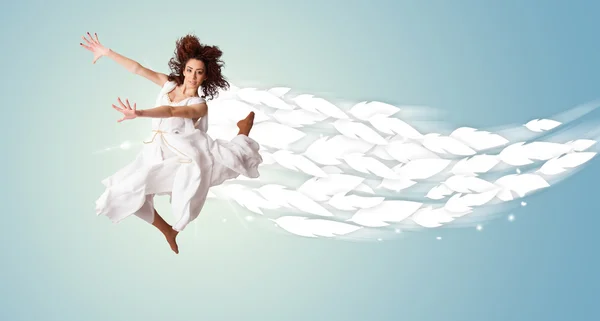Здоровая молодая женщина прыгает с перьями вокруг нее — стоковое фото